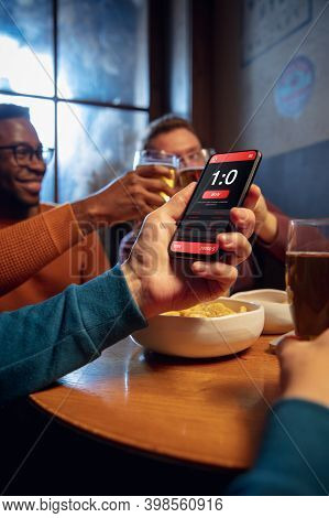 Clinking, Winners. Excited Fans In Bar With Beer And Mobile App For Betting, Score On Their Devices.