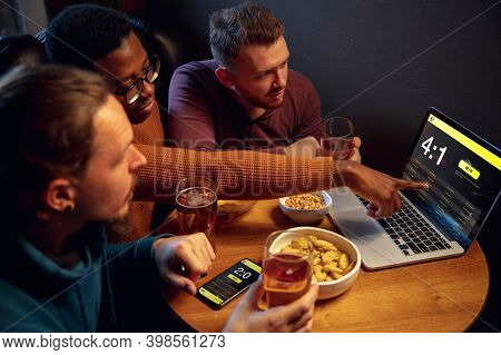 Analyzing. Excited Fans In Bar With Beer And Mobile App For Betting, Score On Their Devices. Screen 