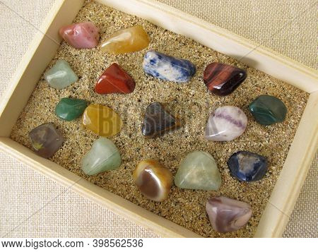 Tumbled Gemstones In A Wooden Box With Sand