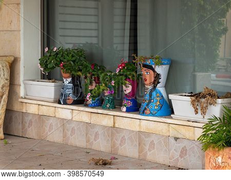 Nazareth, Israel, December 05, 2020 : Flower Pots Painted Like Dolls In National Clothes In The Musl