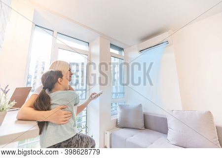 Mother In Sportswear With Daughter Standing Near The Air Conditioning