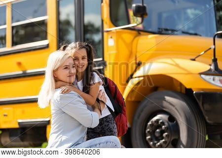 Mother Brings Her Daughter To School Near The School Bus. Back To School