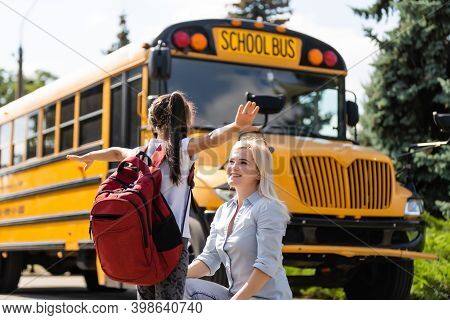 Mother Brings Her Daughter To School Near The School Bus. Back To School
