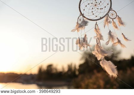 Beautiful Handmade Dream Catcher Near River On Sunny Day. Space For Text