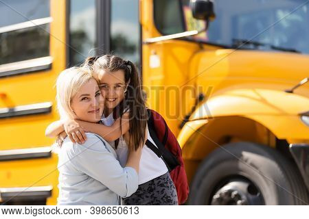 Mother Brings Her Daughter To School Near The School Bus. Back To School