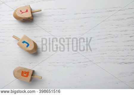 Hanukkah Traditional Dreidels With Letters Nun, Gimel And Shin On White Wooden Background, Flat Lay.