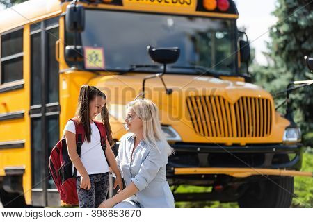 Mother Brings Her Daughter To School Near The School Bus. Back To School