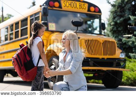 Mother Brings Her Daughter To School Near The School Bus. Back To School