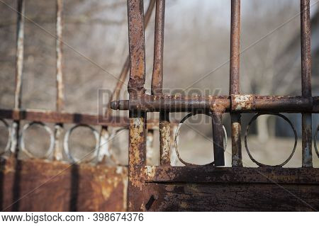 Old Rusty Iron Gate With A Deadbolt. Aged Fence Door Locked By Bolt