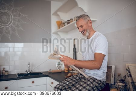 Grey-haired Tall Man Reading A Newspapaer And Looking Interested