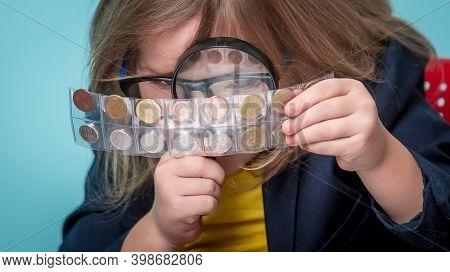 Child Numismatist. Kid With A Magnifying Glass Is Considering The Old Coin Numismatist. Financial Ed