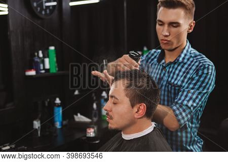 Attractive Young Barber Working With A Customer, Spraing His Hair With Water Before Giving A Haircut