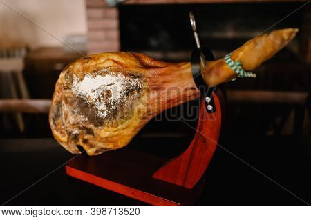 Jamon Serrano. Traditional Spanish Ham Hamon - Whole Leg Of Dried Pork Meat On A Wooden Stand. Bello