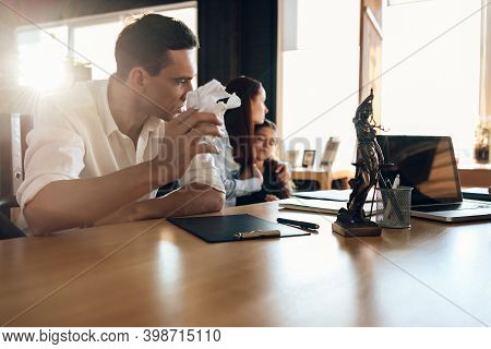 Frustrated Father In Suit Sits On Couch Next To Young Wife And Daughter. A Man Sits In A Suit And Lo