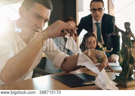 Frustrated Father In Suit Sits On Couch Next To Young Wife And Daughter. A Man Sits In A Suit And Lo