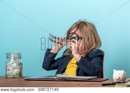 Child Numismatist With Metal Coin In A Transparent Plastic Protection Square Capsule. Kid With A Mag