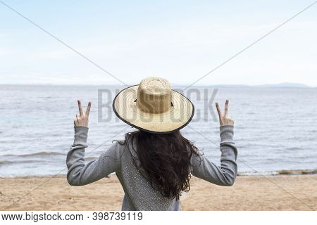 Girl In Vacation With Hat Relaxing Doing Peace And Love With Fingers - Facing The Sea - Tourism And