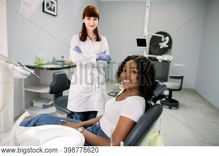 Young Smiling African Female Patient Has Dental Attendance In The Dentists Office, Sitting In The De