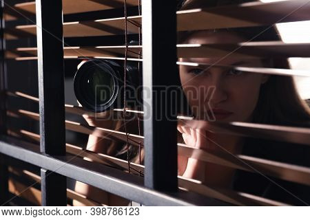 Private Detective With Camera Spying Near Window Indoors, Closeup