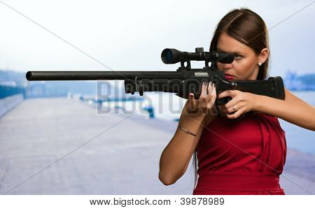 Chica apuntando con pistola a un puerto
