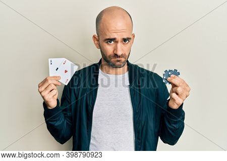 Young hispanic man playing poker holding casino cards and chips depressed and worry for distress, crying angry and afraid. sad expression. 