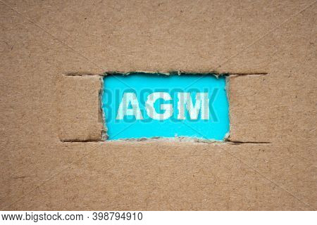 A Cut-out Hole In The Paper Cardboard, And Under It A Piece Of Paper With The Word Agm. The Word Agm