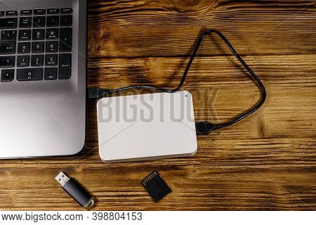 External Hdd Connected To Laptop Computer, Sd Memory Card And Usb Flash Drive On A Wooden Desk. Top 