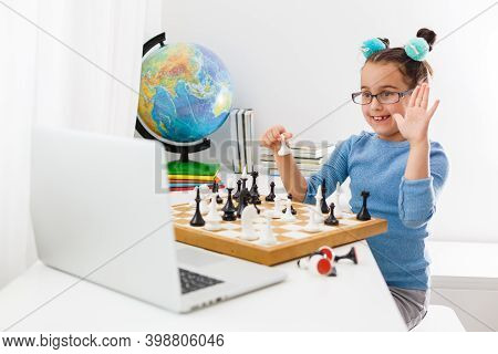 Portrait Caucasian Little Cirly Girl Playing Chess At The Table In Interior With Chessboard. Little 