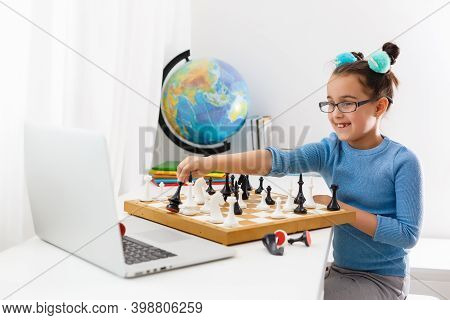 Portrait Caucasian Little Cirly Girl Playing Chess At The Table In Interior With Chessboard. Little 