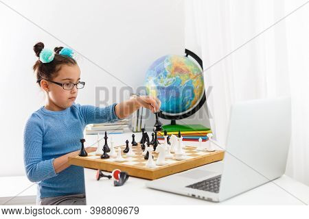 Portrait Caucasian Little Cirly Girl Playing Chess At The Table In Interior With Chessboard. Little 