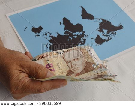 Hand Of A Man Holding Peruvian Money And World Map