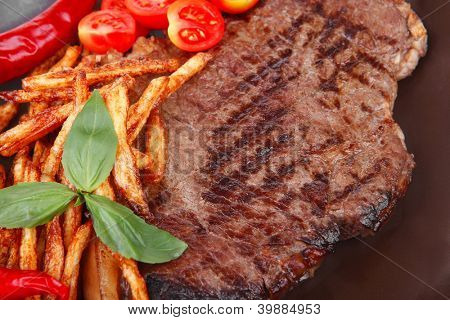 Essen: große Grill Beefsteak auf dunklen Teller mit red hot Chili Pepper und roh Kirschtomate Isola