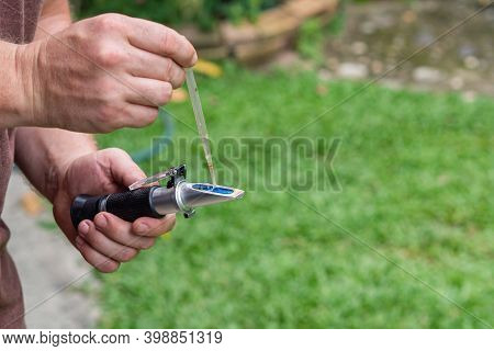 Close-up Of Hands Young Man Holding Refractometer For Measure Craft Beer Sugar Level. Selective Focu