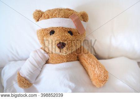 Teddy Bear Is Sick On The Bed, His Arm Is Broken And His Head Is Broken From An Accident.