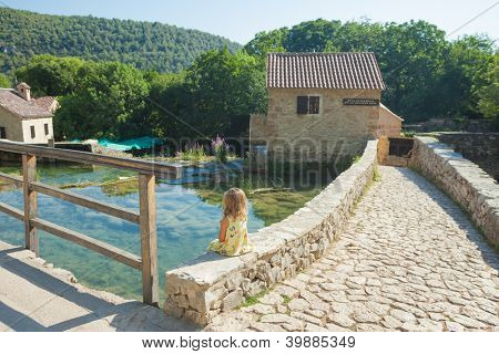 KRKA, Kroatia - 28 heinäkuu 2012: Tyttö istuu seinällä 28. heinäkuuta 2012 Krka, Kroatia. Krka-Nat