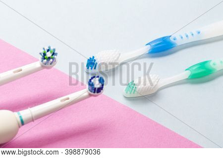Two Professional Electric Toothbrushes Against Manual Brushes On Pink And Blue Background
