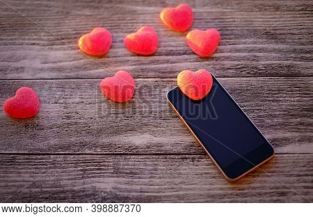 Red Hearts And Black Smart Phone With Blank Screen On Old Wooden Background, Online Communication Da