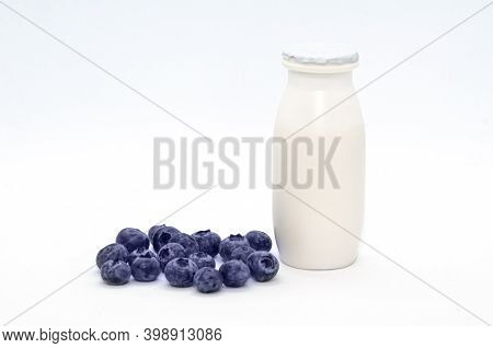Natural Yogurt With Probiotics And Lactobacillus In Small Plastic Bottle And Blueberry On White Back