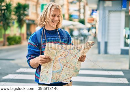 Young scandinavian tourist man smiling happy using map at the city.