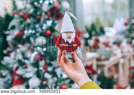 The Girl Is Holding Santa Claus - The Gnome In Her Hands. Against The Background Of A Christmas New