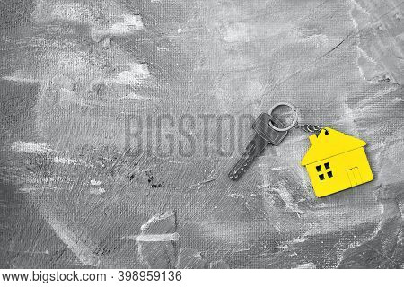 Keys About A Charm Of The House Of Yellow Color On A Gray Background. Top View.color Of The Year 202