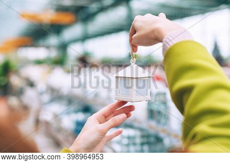 The Girl Holds In Her Hands A Decorative House With Decorations On The Christmas Tree. Against The B