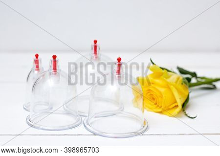 Jars For Hijama On A White Wooden Background And Yellow Flowers. Bloodletting. Sunnah Treatment. Isl