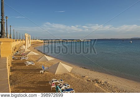 View Across A Sandy Tropical Beach Resort Shoreline With Stone Bridge Walkway And Arches At Sunset