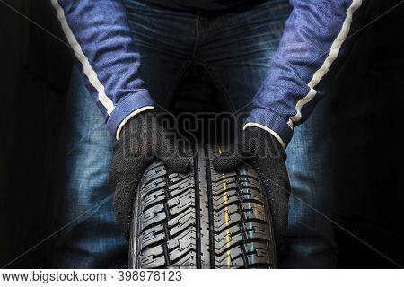Hands Of A Mechanic In Gloves Hold A Tire. Automobile Mechanic With Car Tire. Car Wheel Replacement.