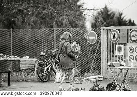 Strasbourg, France - Nov 1, 2020: Rear View Of Woman With Flower Entering Cemetry In France On All S