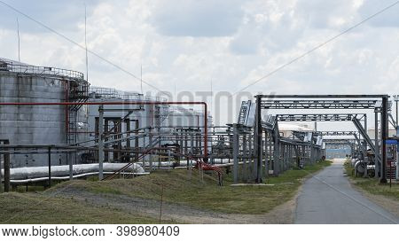 Refinery Factory Oil Storage Tank And Pipeline Steel At Day On Framatic Sky Background. Oil Refinery