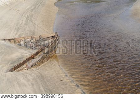 Lines And Patterns Curving Along Edge Of Mill Creek Interupted By Bow Of Old Wooden Boat  Stuck In S