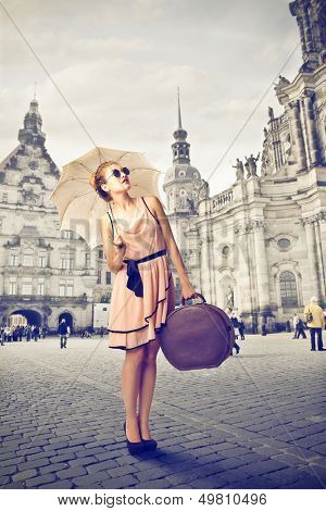 beautiful tourist with umbrella and old suitcase around the city