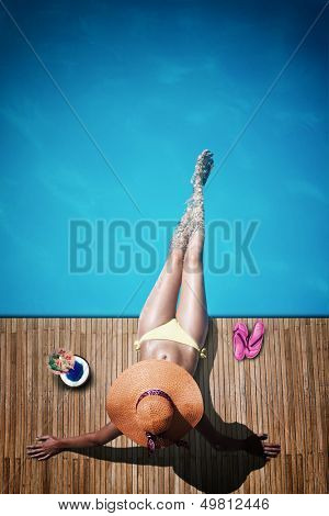 Young woman reaxing on the deck by the swimming pool at exotic resort